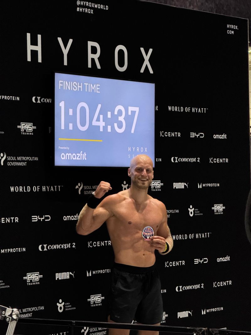 Atleet van Momentom voor het finishbord met een tijd van 1:04:37